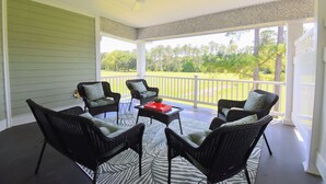 A covered porch with wicker furniture and a view of a green lawn. - Cozy 2-bedroom condo in charming Townsend with WiFi, AC (Townsend)