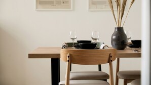 A dining table with a vase of dried plants, two wine glasses, and black bowls. - Stylish Apartment in Berlin Mitte (Berlin)