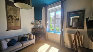Habitació amb sofà, finestra amb cortines, radiador i làmpada.