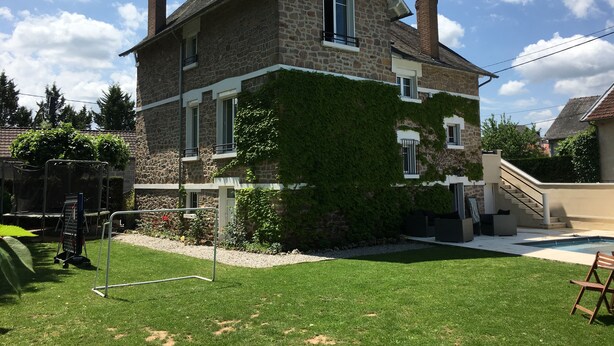 Una casa de pedra amb un porxo cobert, una piscina petita i un jardí amb gespa.