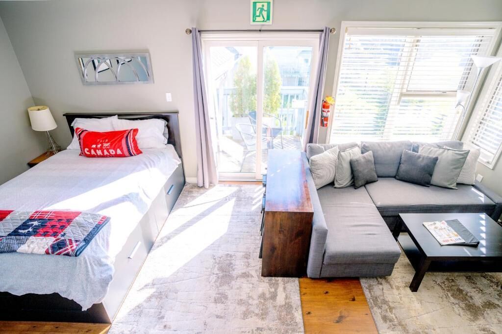 A hotel room with two beds, a sofa, a coffee table, and a view of the outside.