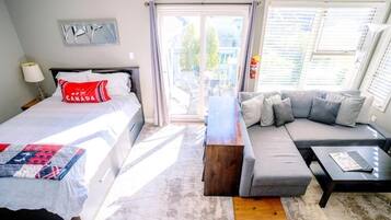 A hotel room with two beds, a sofa, a coffee table, and a view of the outside.