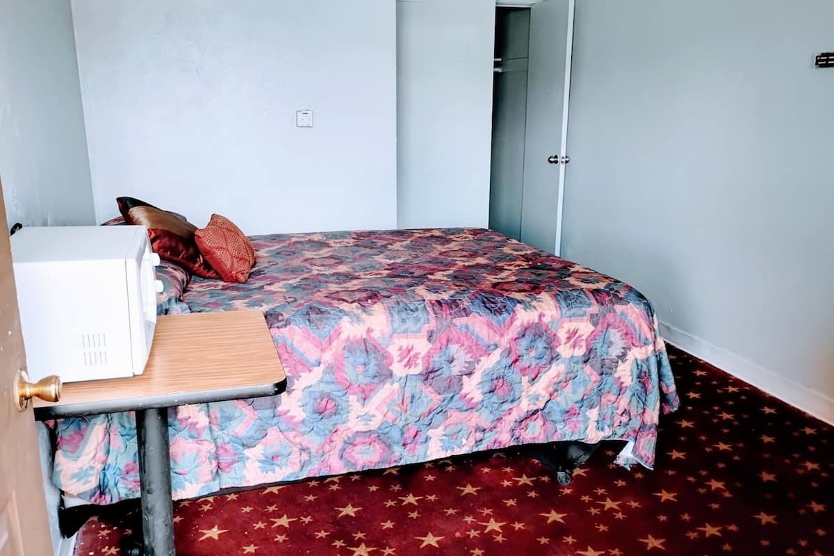 Un dormitorio con cama, una mesita, un armario y una alfombra con motivos de estrellas.