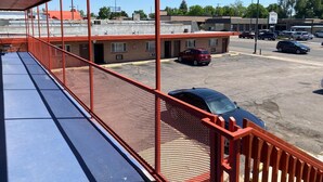 A covered outdoor area with a red railing, a parking lot, and several buildings in the background. - Hotel O Englewood-South Denver CO (Englewood)
