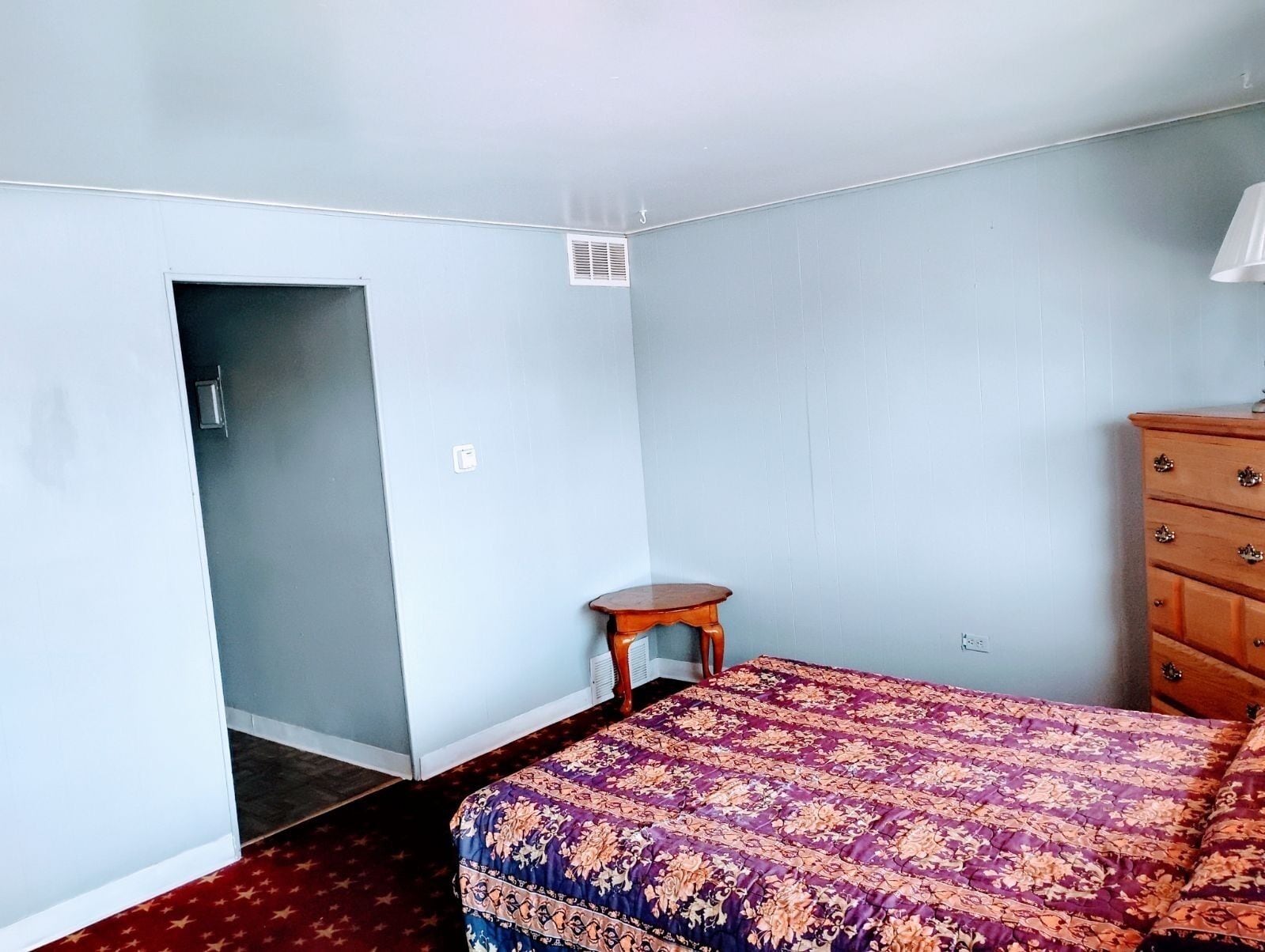 Un dormitorio con cama, cómoda y una mesita.