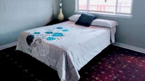A bedroom with a bed, a window with curtains, and a wall with a brick pattern. - Hotel O Englewood-South Denver CO (Englewood)