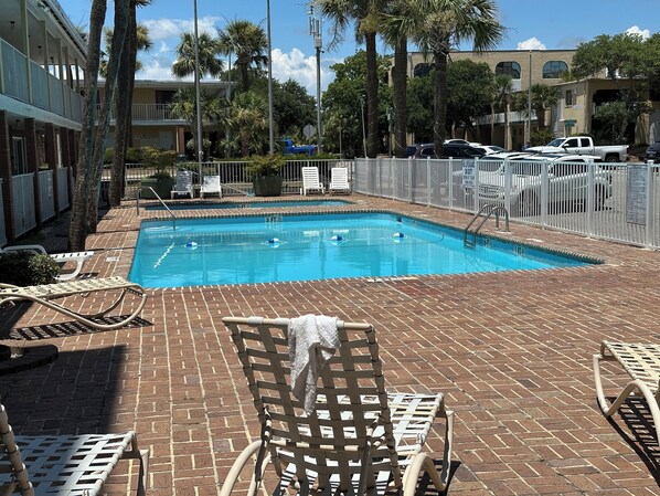 A swimming pool with lounge chairs and a fenced area. - Capital O Sunset Waves Hotel Myrtle Beach Oceanfront (Myrtle Beach)