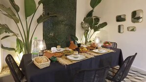 Une table à manger dressée avec différents plats, une bouteille d’eau et une lampe.