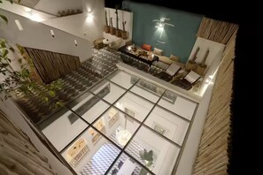 Un intérieur à plusieurs niveaux doté d’un plancher en verre, d’un coin repas et d’une collection de cactus fixée au mur.