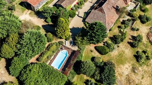 Vue aérienne d’un quartier résidentiel avec une piscine, plusieurs maisons et de nombreux espaces verts.