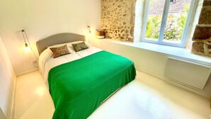 A bedroom with a bed, a stone wall, a window, and a radiator. - Charming historic barn with pool (Lembras)