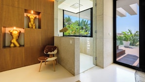 Un baño moderno con cabina de ducha de vidrio, paneles de madera y una zona de estar con una silla.