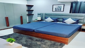 Een moderne slaapkamer met een groot bed, nachtkastjes, een nachtkastje, een wandairconditioner en een lijstwerk met kunst.