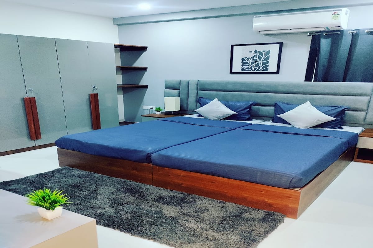 Un dormitorio moderno con una cama grande, mesitas de noche, un aparador y aire acondicionado de pared, además de una obra de arte enmarcada.