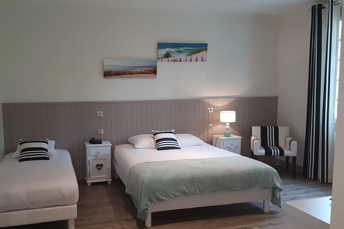 Een hotelkamer met twee bedden, een nachtkastje met een lamp, een stoel en kunst aan de muur.