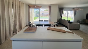 Ein modernes Wohnzimmer mit Essbereich, großen Fenstern und Blick auf einen Garten.