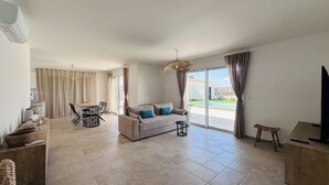 Ein geräumiges Wohnzimmer mit einer Couch, einem Esstisch und einem Fernseher.
