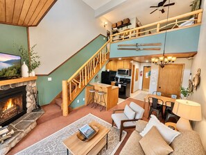 A cozy living room with a fireplace, a dining area, and a kitchen. - Mountainside Ski-In/Ski-Out | Pool & Hot Tub (Lutsen)