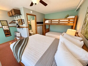 Ein Schlafzimmer mit Etagenbetten, einem Deckenventilator, einem Nachttisch mit Lampe und einem Wandregal mit verschiedenen Gegenständen.