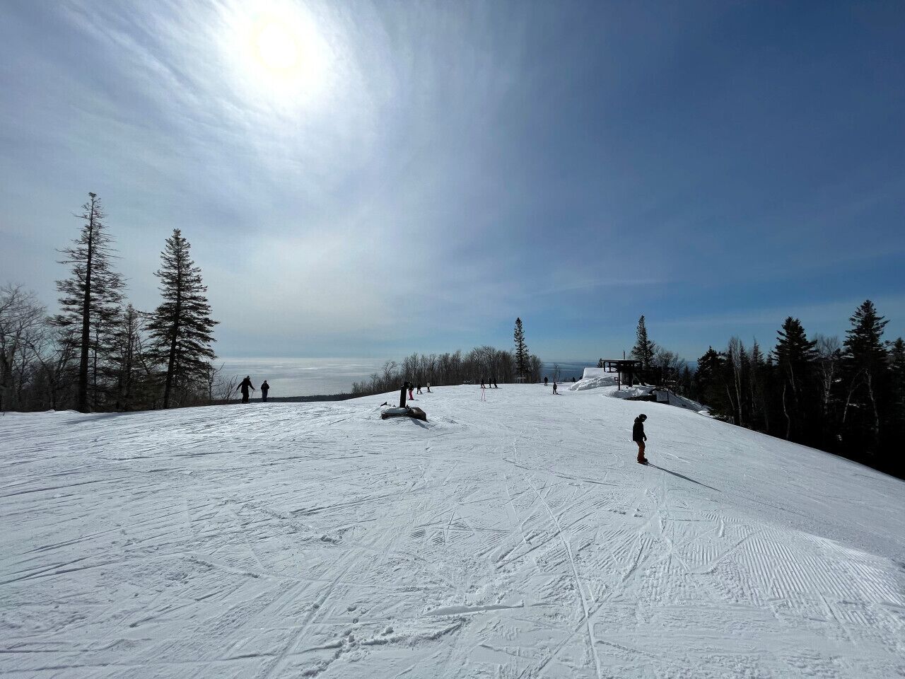A snowy ski slope with skiers and a clear sky.