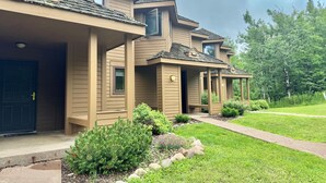 A row of two-story houses with a covered porch, a well-maintained lawn, and a clear sky. - Family-Friendly Ski-In/Ski-Out | In-Unit Sauna (Lutsen)