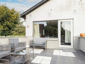 A patio area with outdoor furniture, a glass door leading to a covered space, and a view of the surrounding greenery. - 6 Person Holiday Home in Borre (Borre)