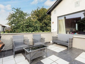 An outdoor patio with wicker furniture and a tiled floor.