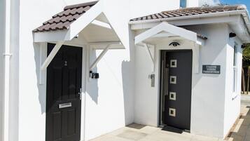 A white building with two black doors, one with a small porch and a sign above it.