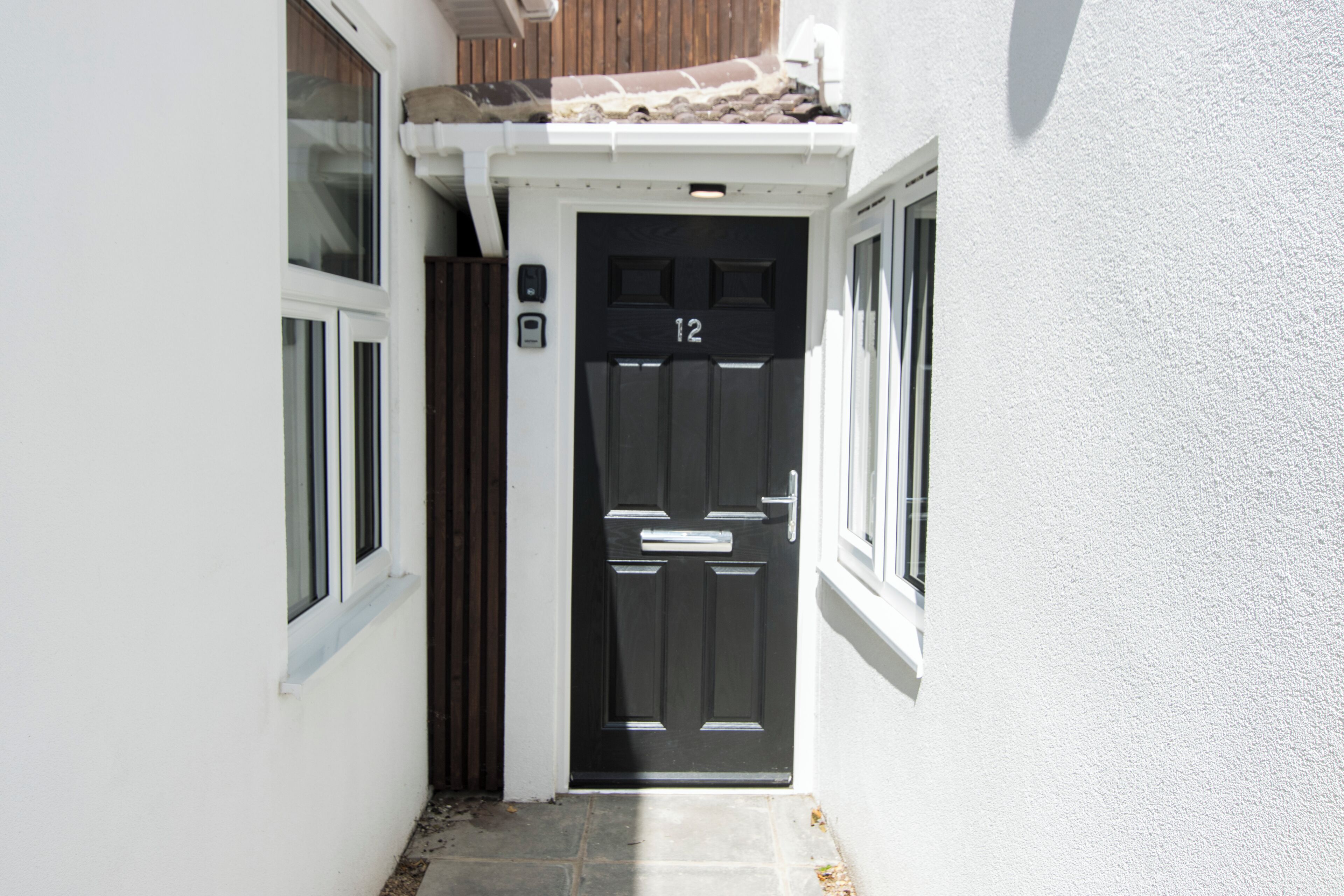 A black door with the number 12, white walls, and a small window to the left.