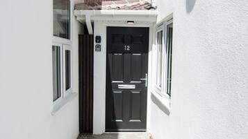 A black door with the number 12, white walls, and a small window to the left.