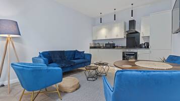 A modern living room with a blue sofa, matching chairs, and a dining table.