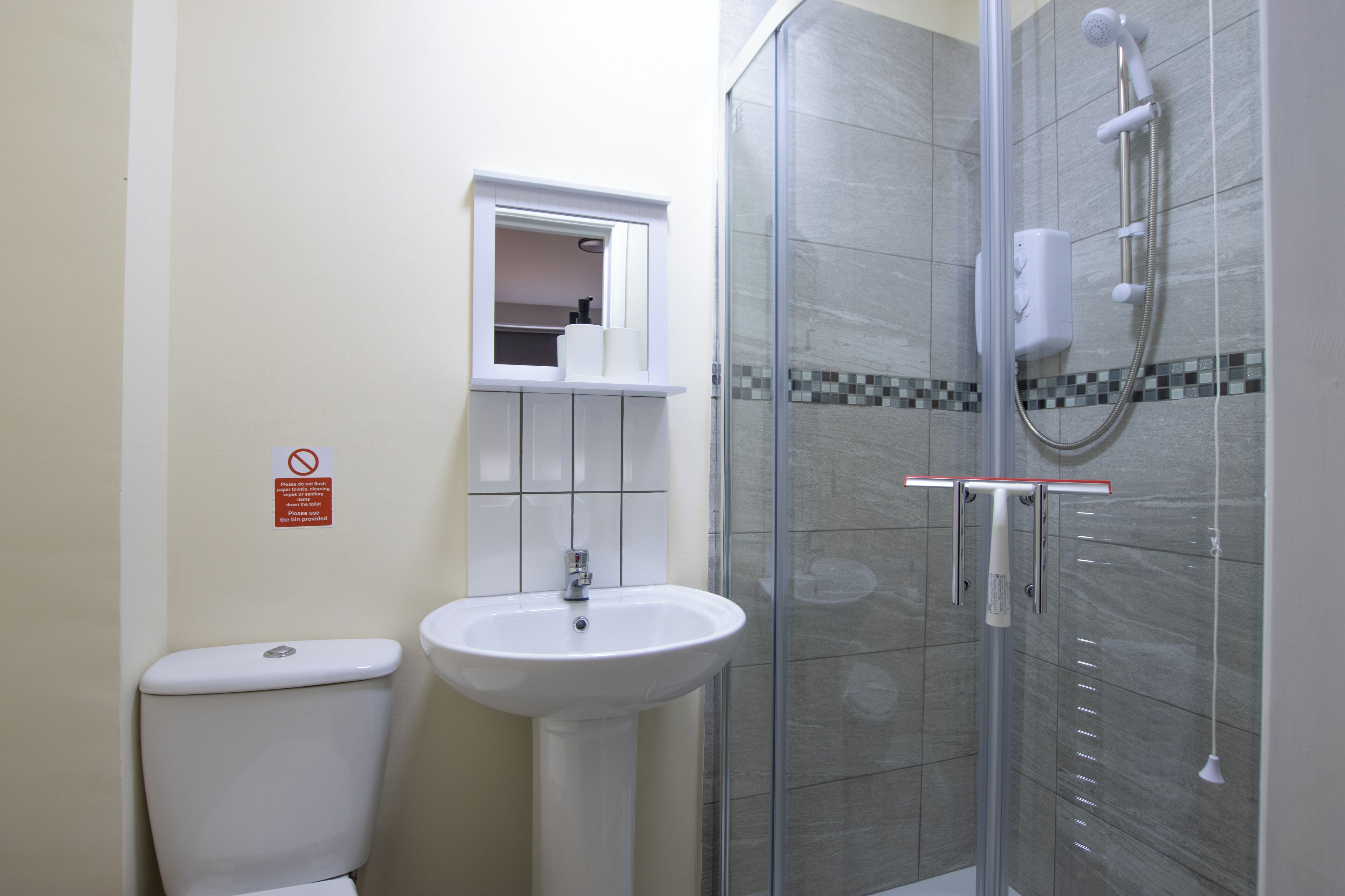 A bathroom with a toilet, sink, and glass-enclosed shower area.