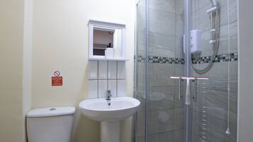 A bathroom with a toilet, sink, and glass-enclosed shower area.