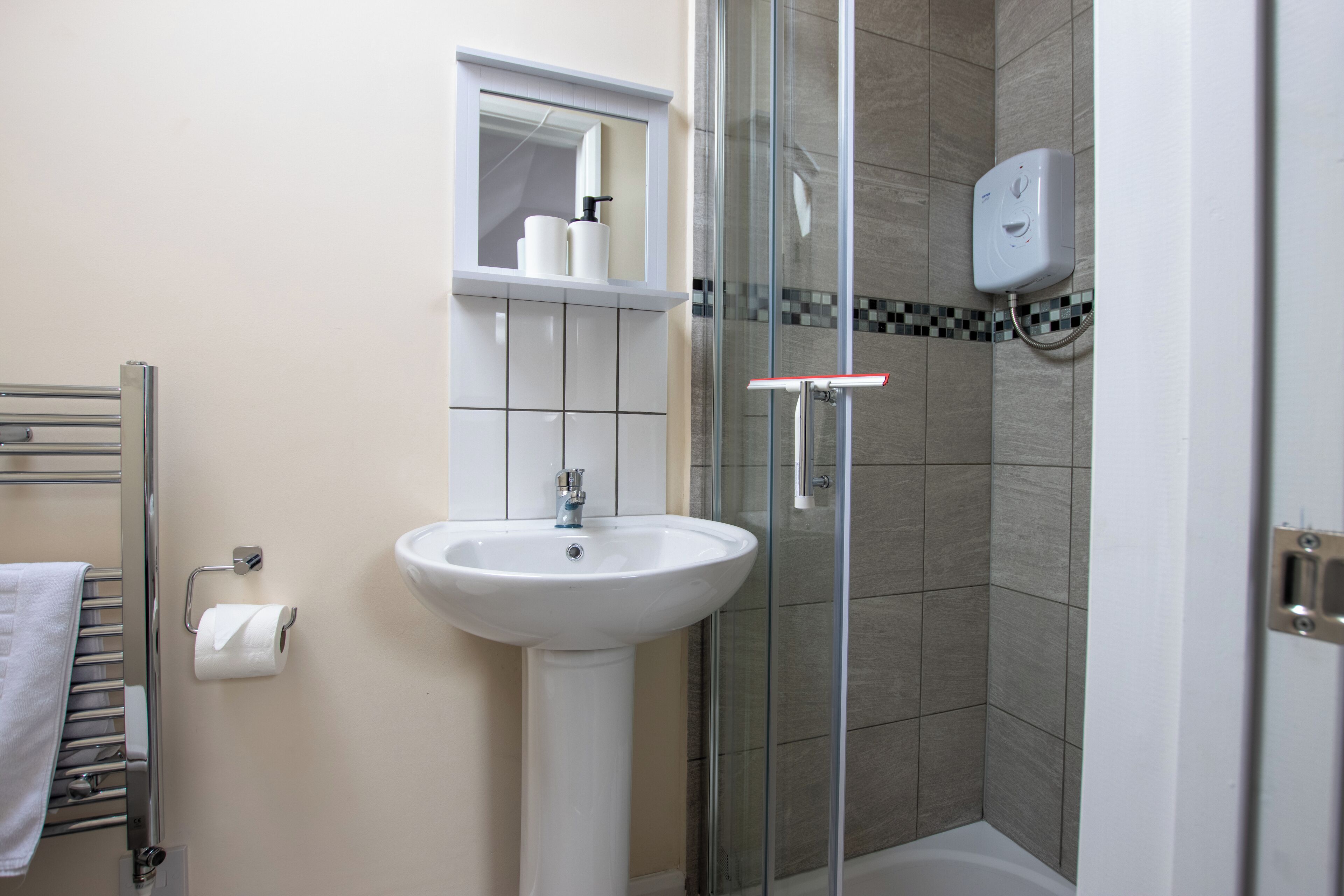 A bathroom with a white sink, a glass shower enclosure, a towel rack, and a mirror.