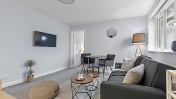 A modern living room with a grey sofa, round coffee table, and a TV mounted on the wall.