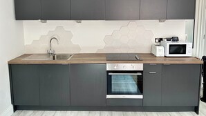 Een moderne keuken met donkere kastjes, een roestvrijstalen spoelbak, een magnetron en een oven.