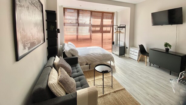 Een moderne slaapkamer met een bed, een bank, een bureau en een televisie.