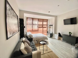 Un dormitorio moderno con cama, sofá, escritorio y televisor.