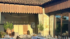 Een lange eettafel gedekt voor een formeel evenement, met witte tafelkleden, kaarsen en bloemstukken.