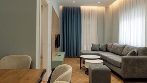Uma sala de estar moderna com um sofá seccional, uma mesa de centro redonda e um espaço de jantar com mesa e cadeiras de madeira.