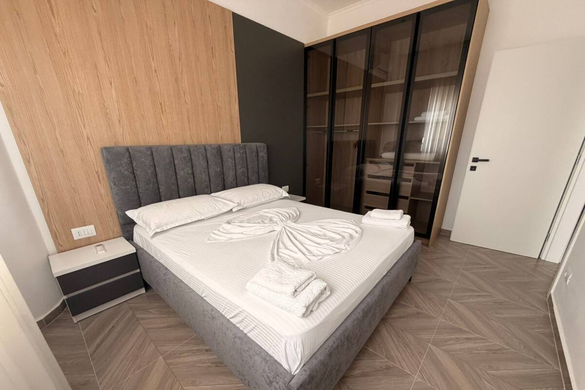 Un dormitorio moderno con una cama grande, un panel de pared de madera, un armario y una puerta.