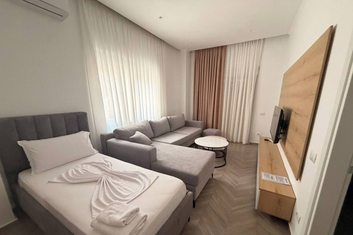 Una habitación de hotel con una cama, un sofá, una mesita y un televisor.