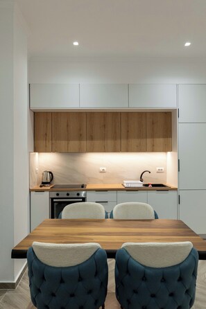 Une cuisine moderne avec des meubles en bois, un four encastré et une table à manger avec des chaises rembourrées.