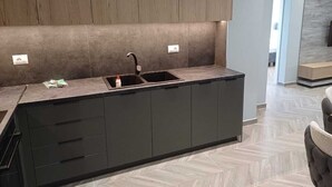 Cozinha moderna com bancada escura, duas pias e armários embutidos.