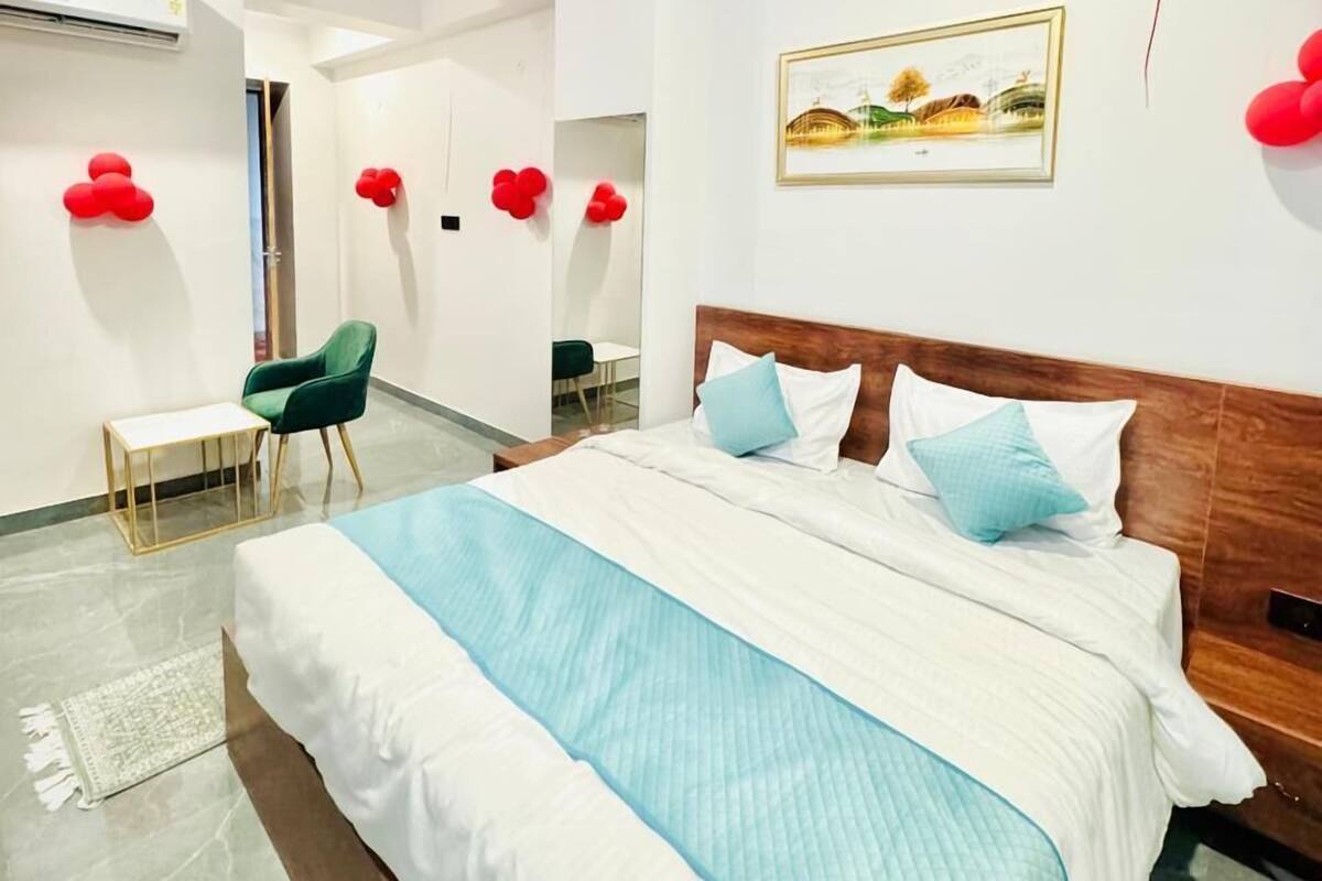 A modern hotel room with a large bed, a desk, a chair, and a ceiling fan.