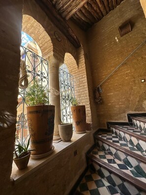 A corridor with arches, potted plants, and a checkered floor. - Suite Double Deluxe (kairouan)