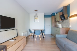 Un espace de vie moderne comprenant un coin repas, une kitchenette et un téléviseur à écran plat fixé au mur.