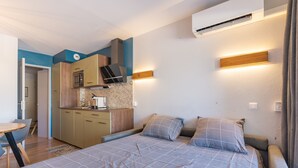 Un dormitorio con cama, mesitas de noche, un escritorio y kitchenette.