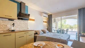 Una cocina moderna con comedor, una cama y un balcón con sillas.
