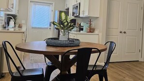 A dining area with a round table, black chairs, a chandelier, and white cabinets. - The Cottages 2 2BR2BA Dothan Pet Friendly Gorgeous Pool, Pickle Ball court, Gym (Dothan)